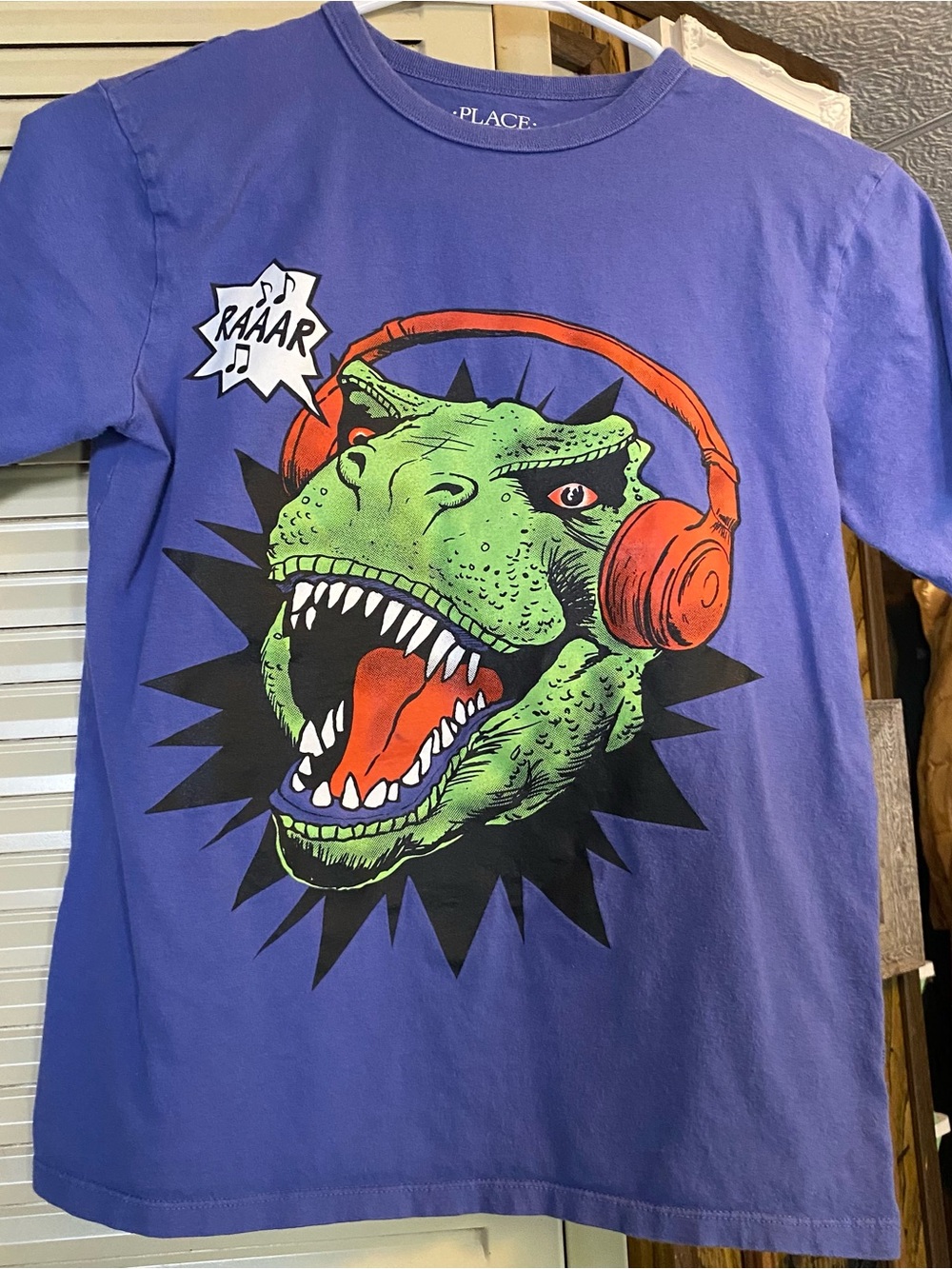 Place Purple Tee with Green T-Rex Wearing Orange Headphones